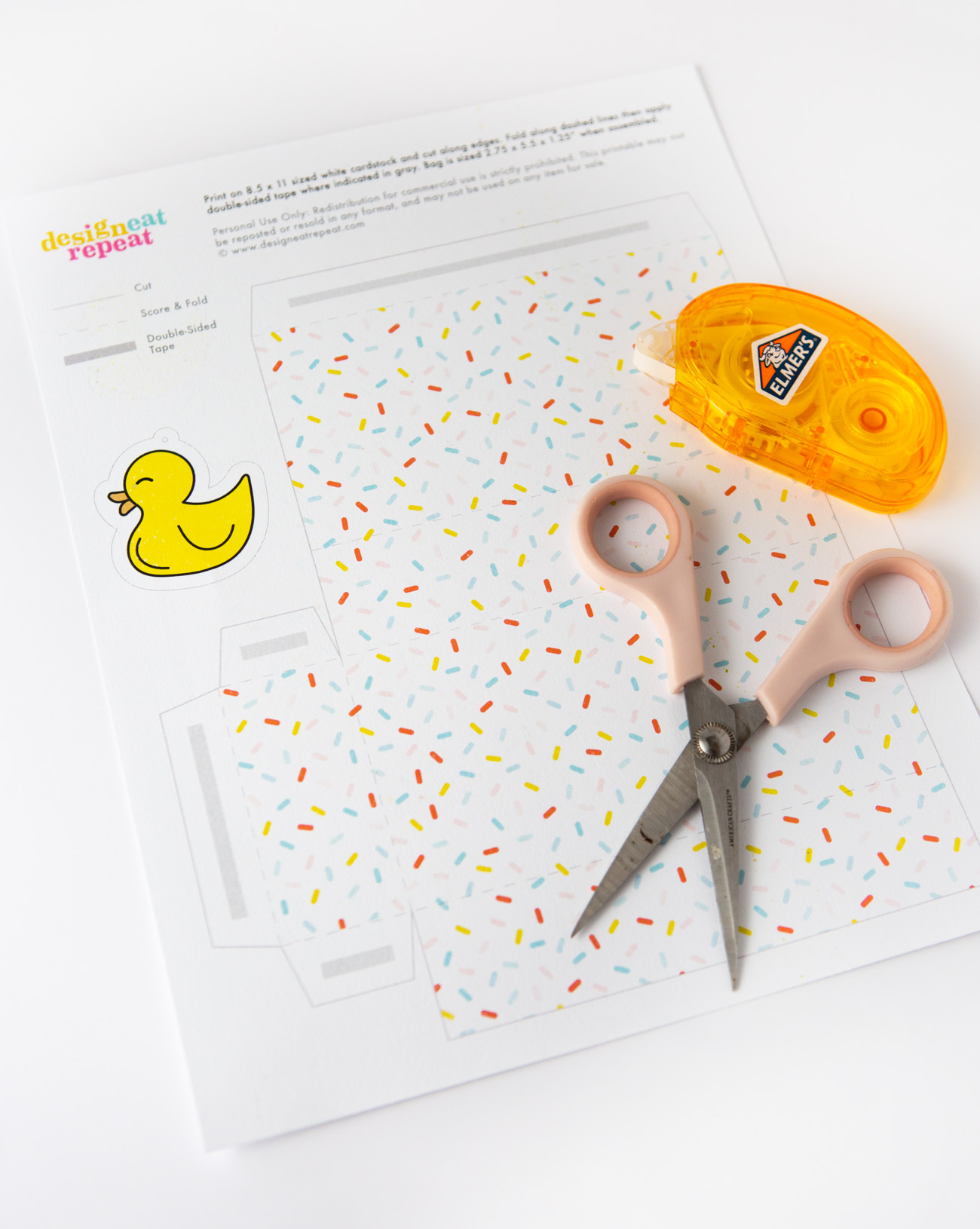 Printed sheet with scissors and tape of pattern baby shower favor bag with rubber duck tag