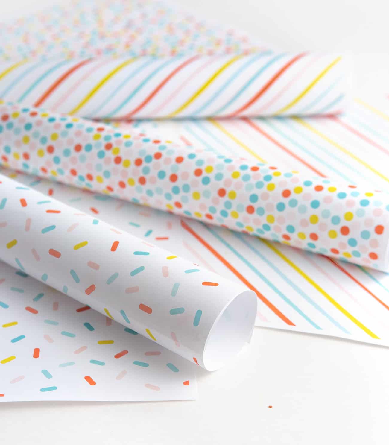 Free printable birthday wrapping paper gift box with blue yay tag and pink pom pom. Patterns include rainbow polka dot, rainbow sprinkle, and rainbow stripe.