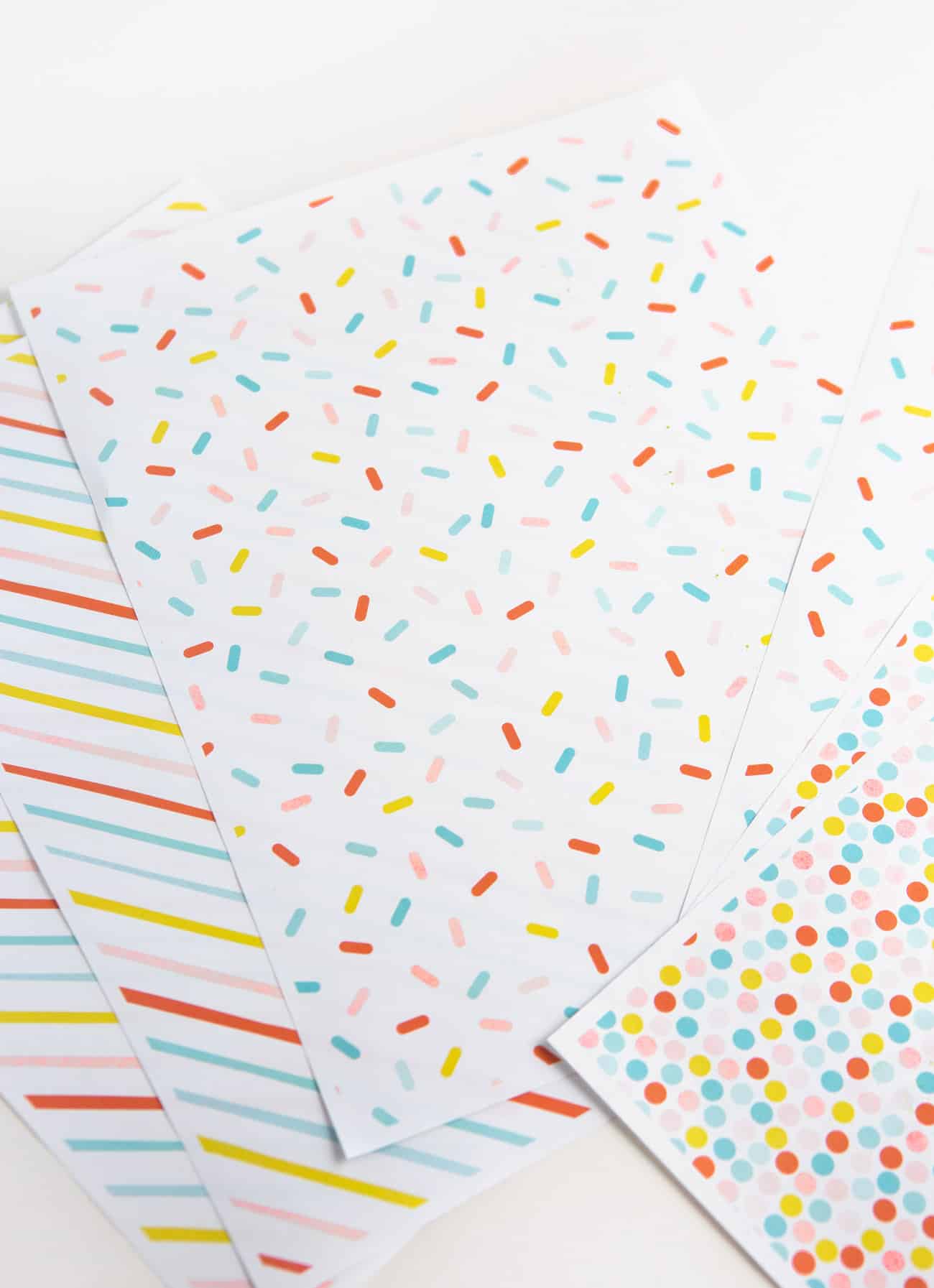 Free printable birthday wrapping paper gift box with blue yay tag and pink pom pom. Patterns include rainbow polka dot, rainbow sprinkle, and rainbow stripe.