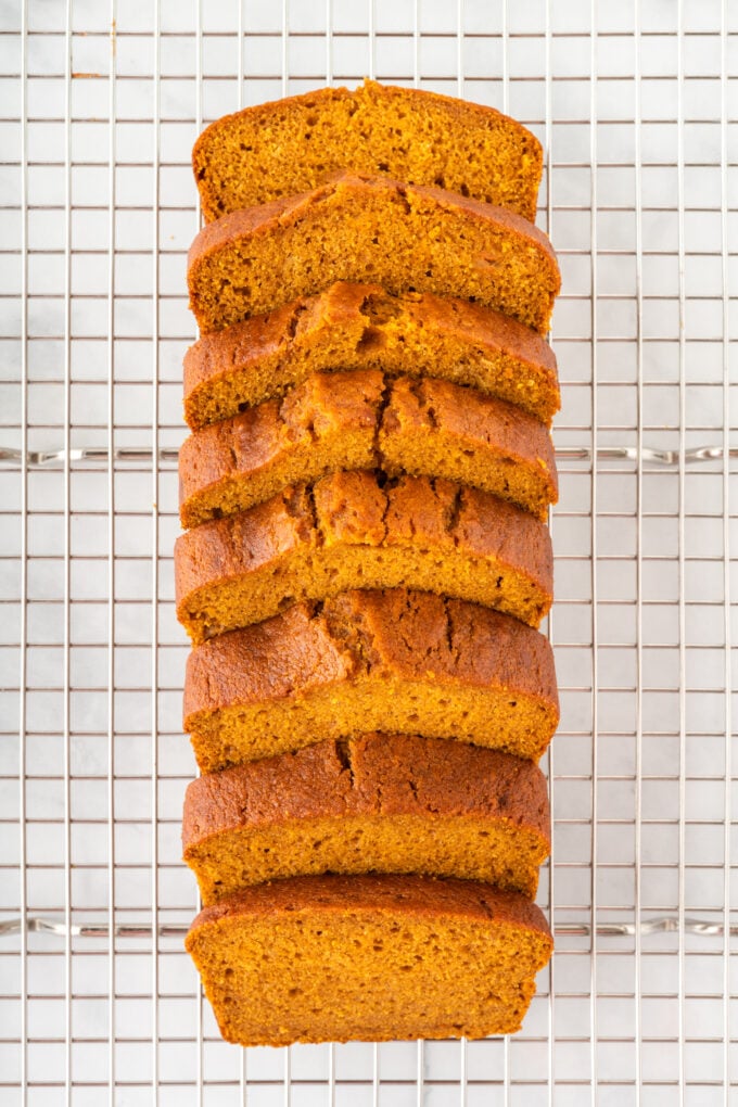 Sliced pumpkin bread sitting stacked on a cooling rack 