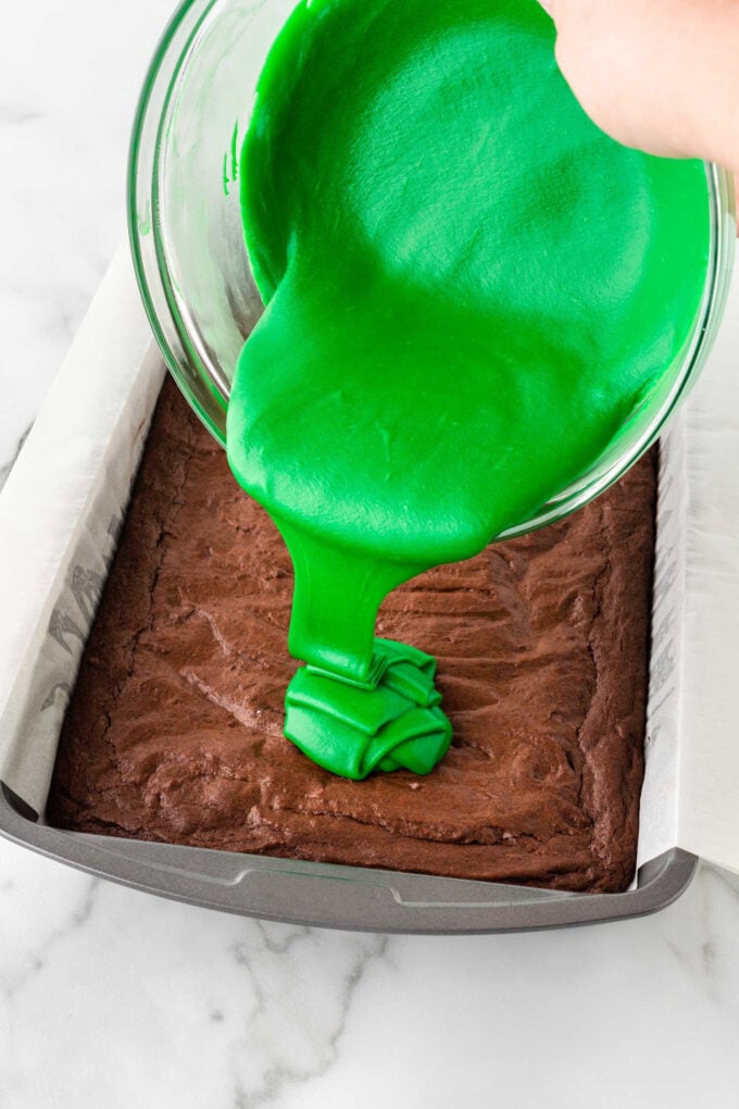 pouring green white chocolate on pan of brownies