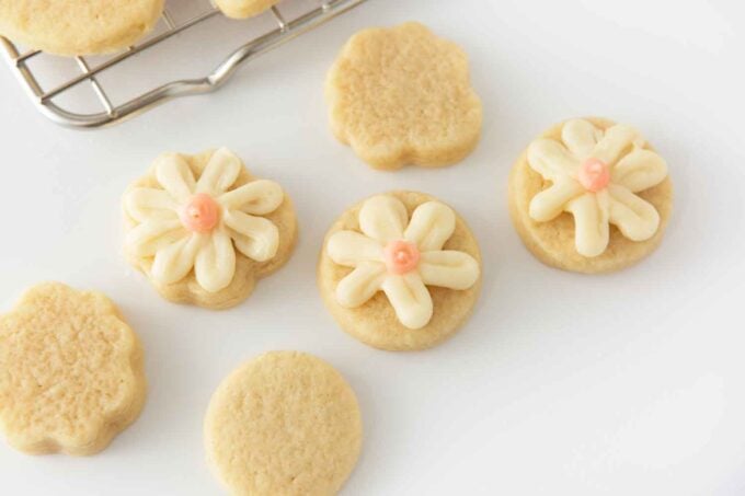 Small circle sugar cookies decorated with white and pink frosting to look like flowers