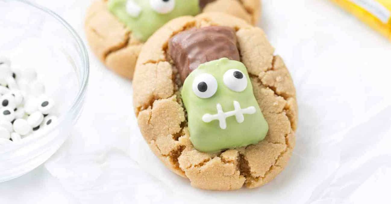 Close up shot of peanut butter cookies topped with Butterfinger fun size candy bars that have been decorated to look like Frankenstein.