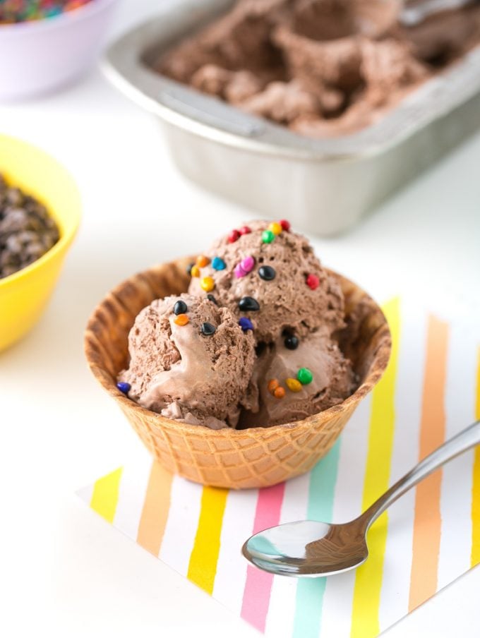Scoop of chocolate no-churn ice cream with rainbow chips in waffle bowl
