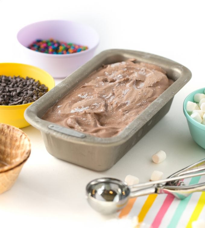 Chocolate no-churn ice cream in metal loaf pan with toppings and scoop