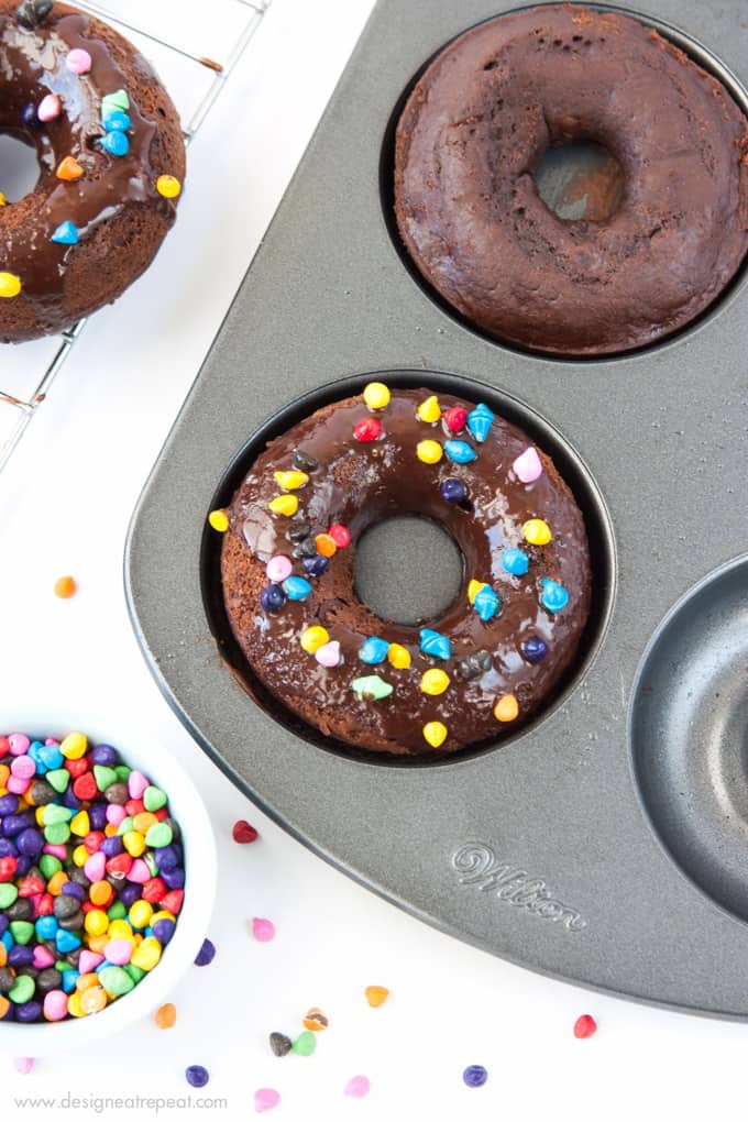Cosmic Triple Chocolate Cake Donuts on in donut pan with rainbow sprinkles