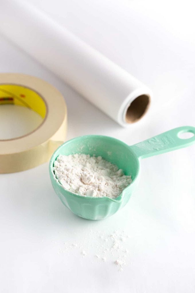 Materials for Roll Out Sugar Cookies - Measuring cup of flour, roll of parchment paper, and masking tape