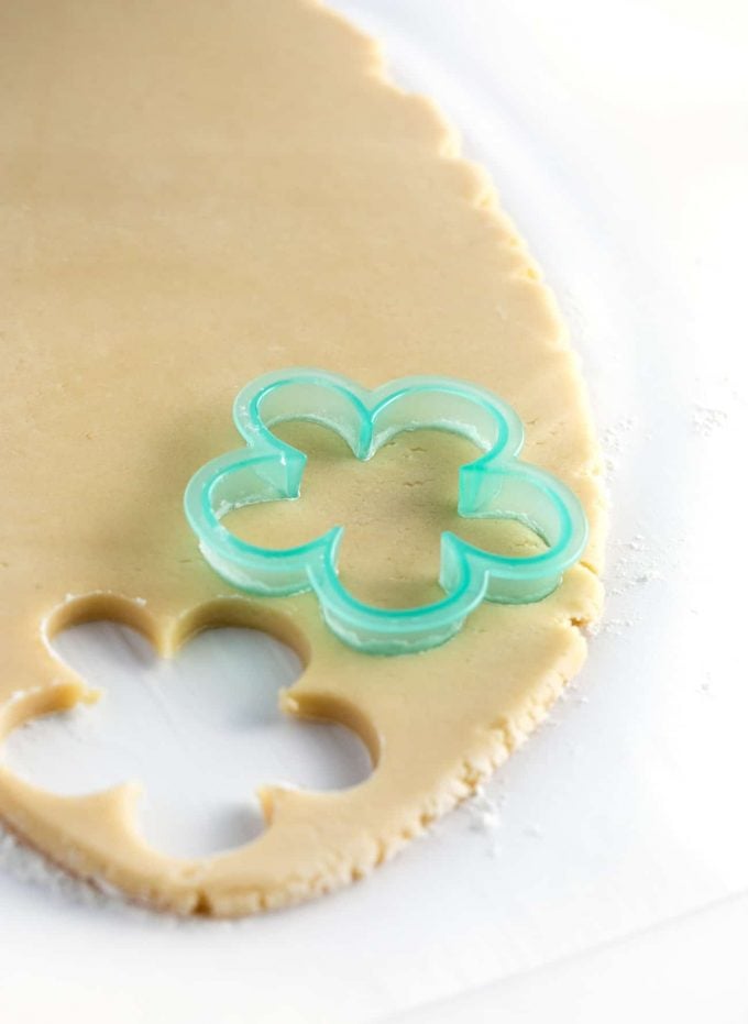 Blue flower cookie cutter cutting out sugar cookie dough