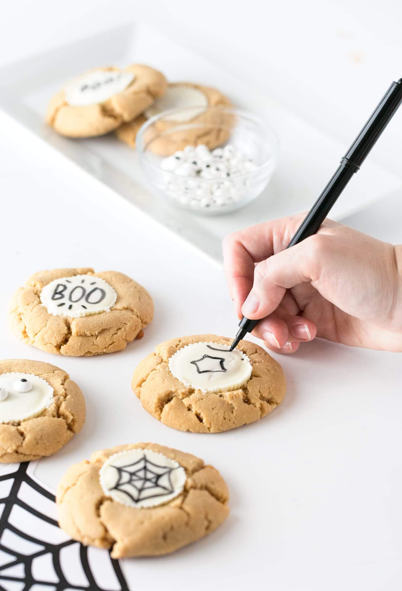 Forget the fancy decorating and grab the edible food pen to draw-your-own easy Halloween cookies! Using a traditional peanut butter cup as the "canvas", you can customize with your own icons, faces or spooktacular phrases! #Halloween | #Cookies | www.DesignEatRepeat.com
