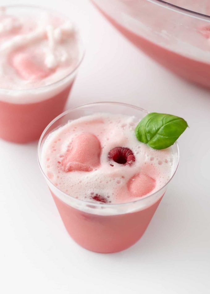 Cup of Raspberry Sherbet Punch with fresh raspberries and basil leaf
