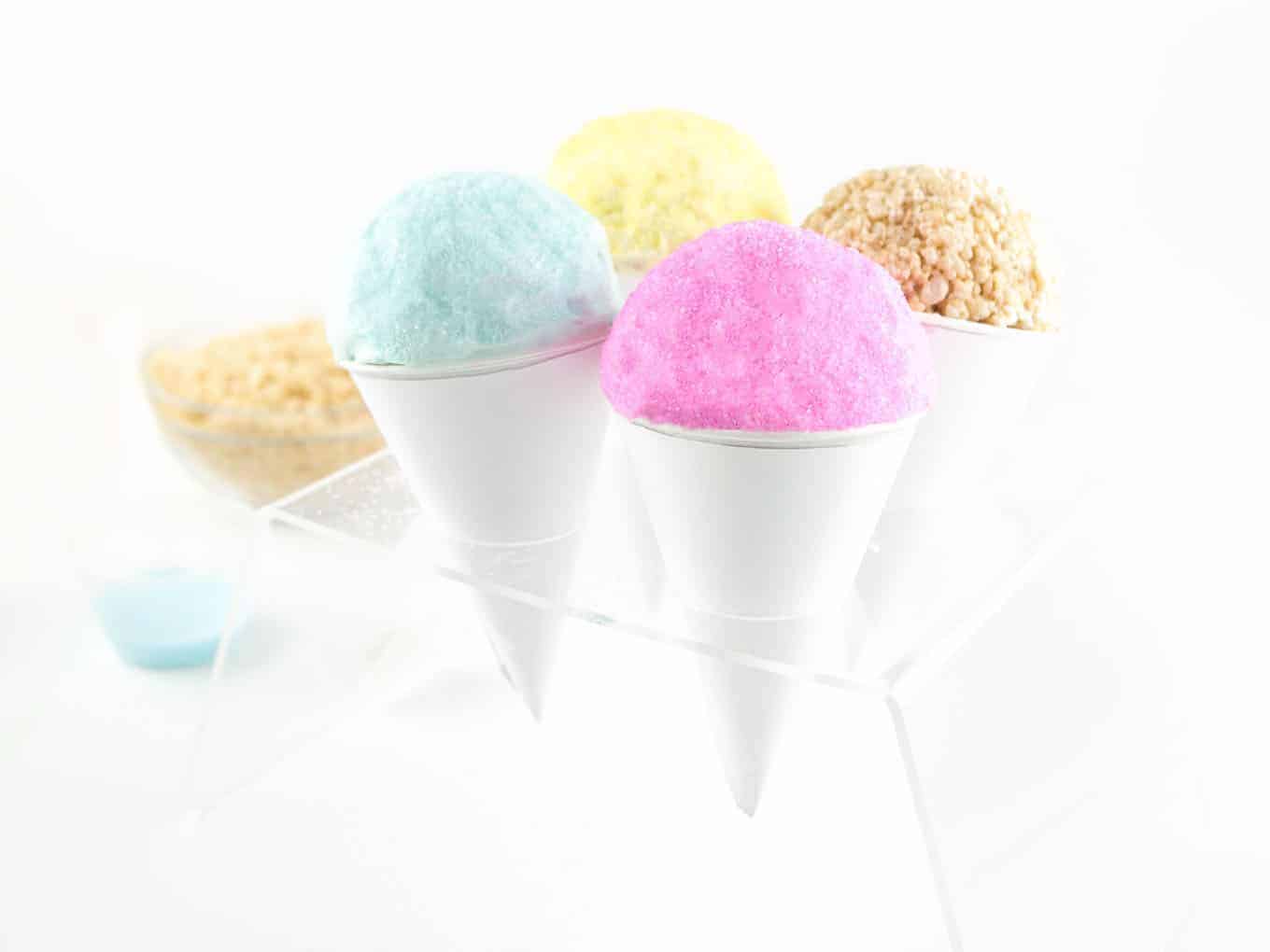 Pink, blue, and yellow rice krispie snowcones in ice cream cone holder.