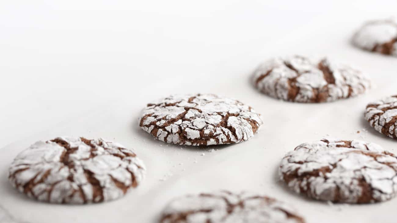 Baking sheet of baked crackle top chocolate brownie cookies.