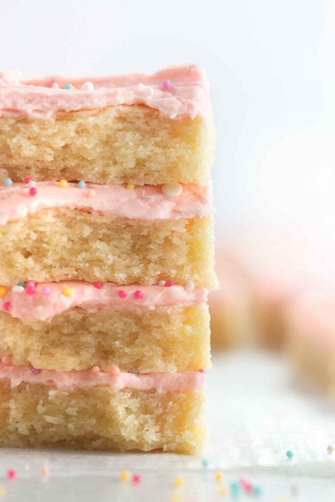 Stack of soft frosted sugar cookie bars with pink frosting and sprinkles