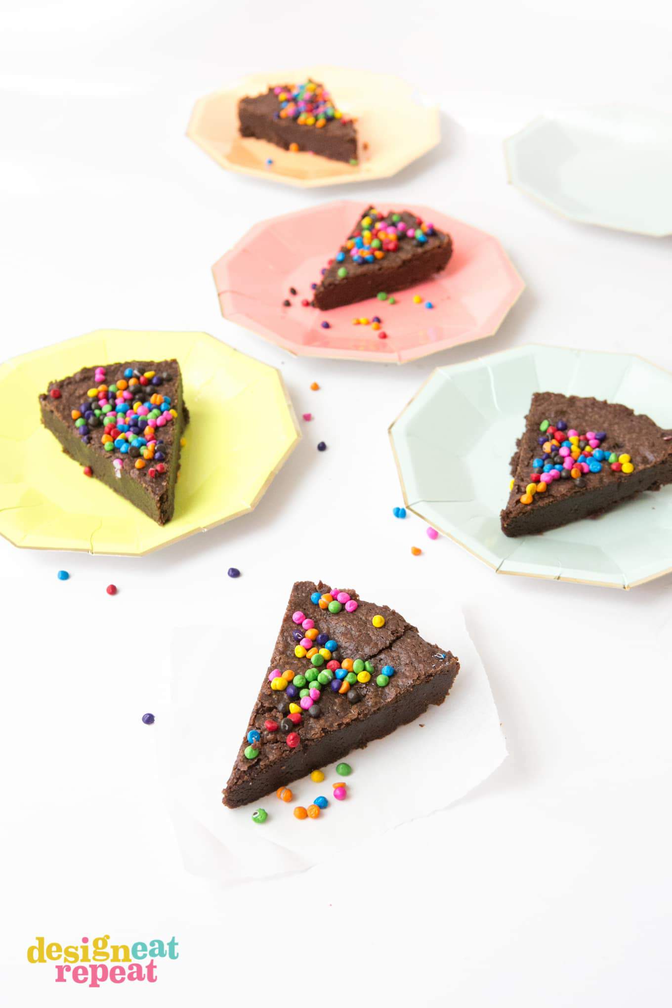 Triangle slices of brownie pie with rainbow chocolate chip sprinkles on top.